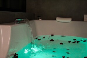 Una bañera con agua entrando, que contiene pétalos de rosa.