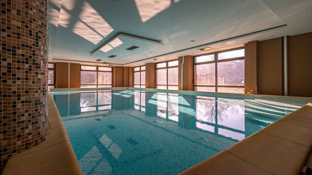 Una piscina interior con agua cristalina, ventanas amplias y pared de azulejos.