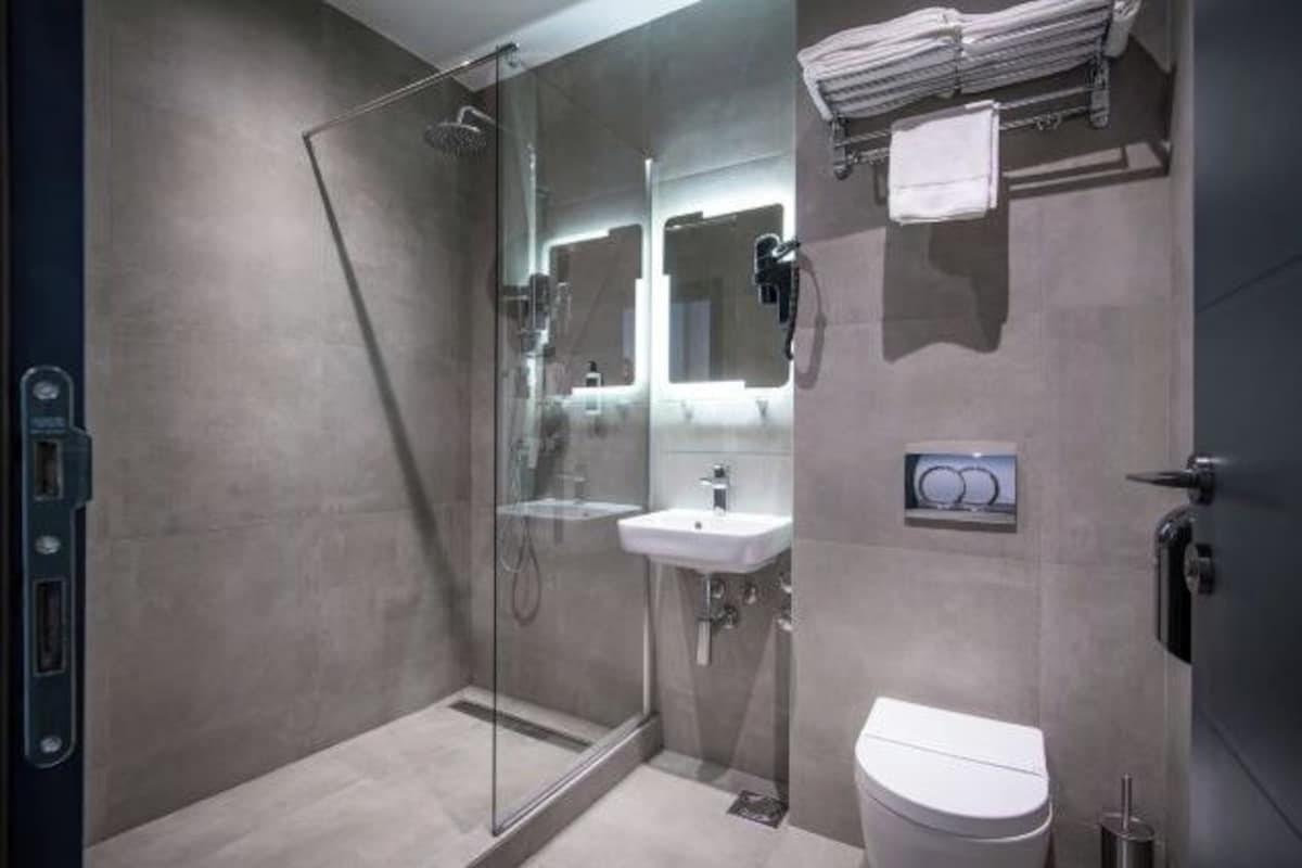 A modern bathroom with a glass-enclosed shower, a white sink, and a toilet.