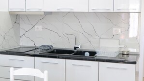 Une cuisine moderne avec des meubles blancs, un plan de travail noir et un pare-feu en marbre.