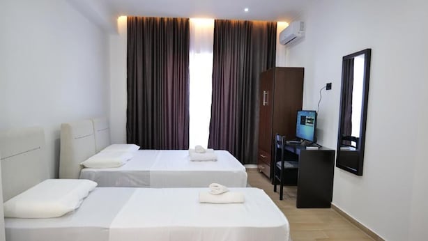 Une chambre d’hôtel avec deux lits, un bureau, une chaise, une télévision et une armoire.