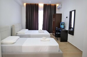 Une chambre d’hôtel avec deux lits, un bureau, une chaise, une télévision et une armoire.