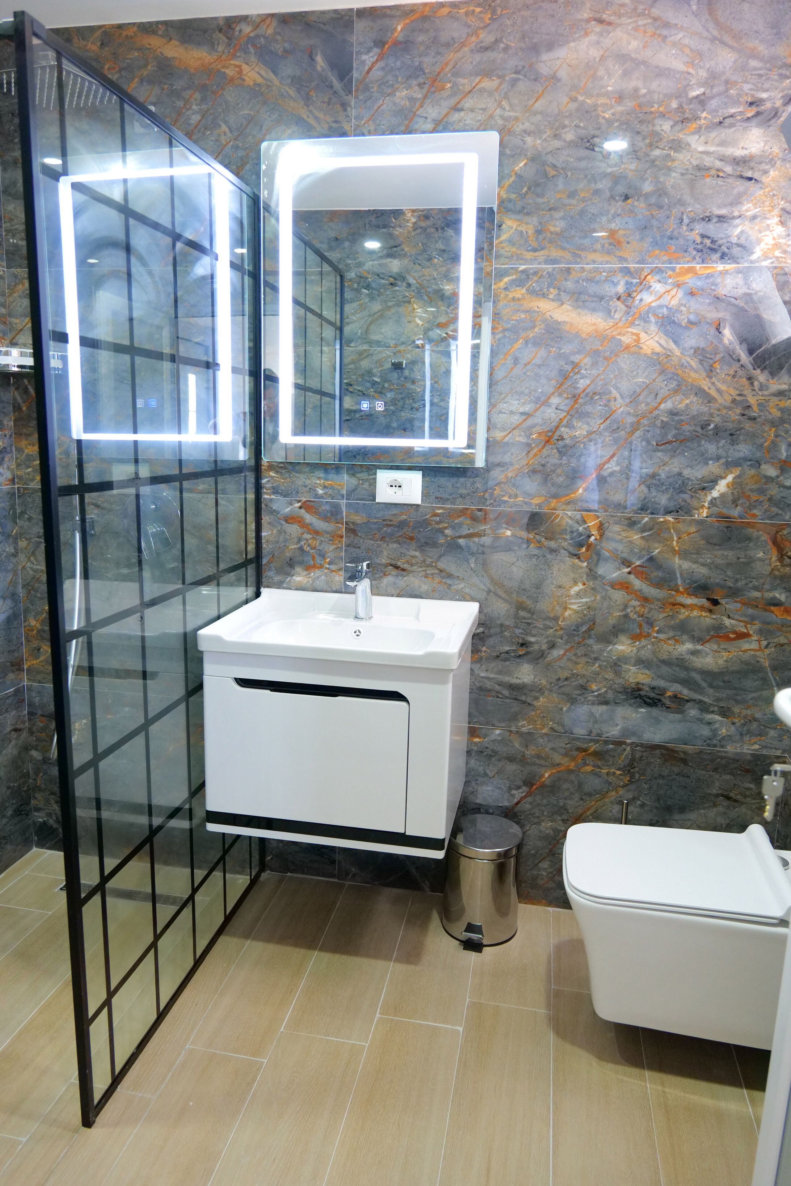 A modern bathroom with a glass shower enclosure, a white sink with a mirror, and a toilet.