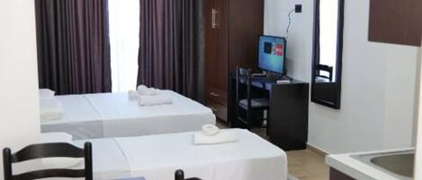 A hotel room with two beds, a desk, a chair, a TV, and a mirror.