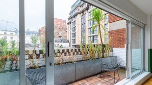 A balcony with a view of a cityscape, featuring a metal chair and a table. - Cosy 1bedroom Flat - 2 Min Walk to Kensington Gardens! (London)