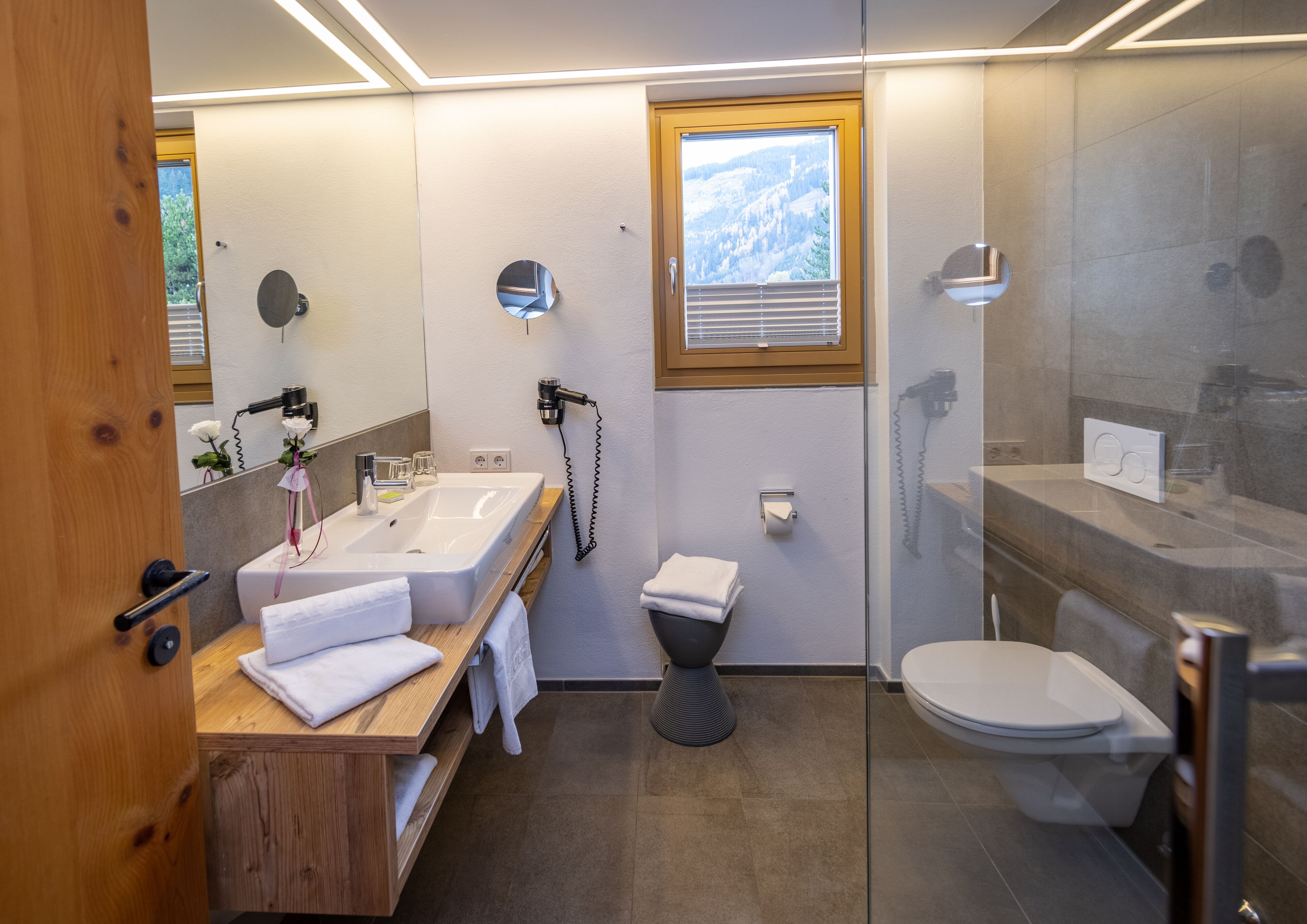 A modern bathroom with a wooden vanity, a toilet, and a shower area.
