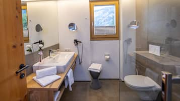 A modern bathroom with a wooden vanity, a toilet, and a shower area.