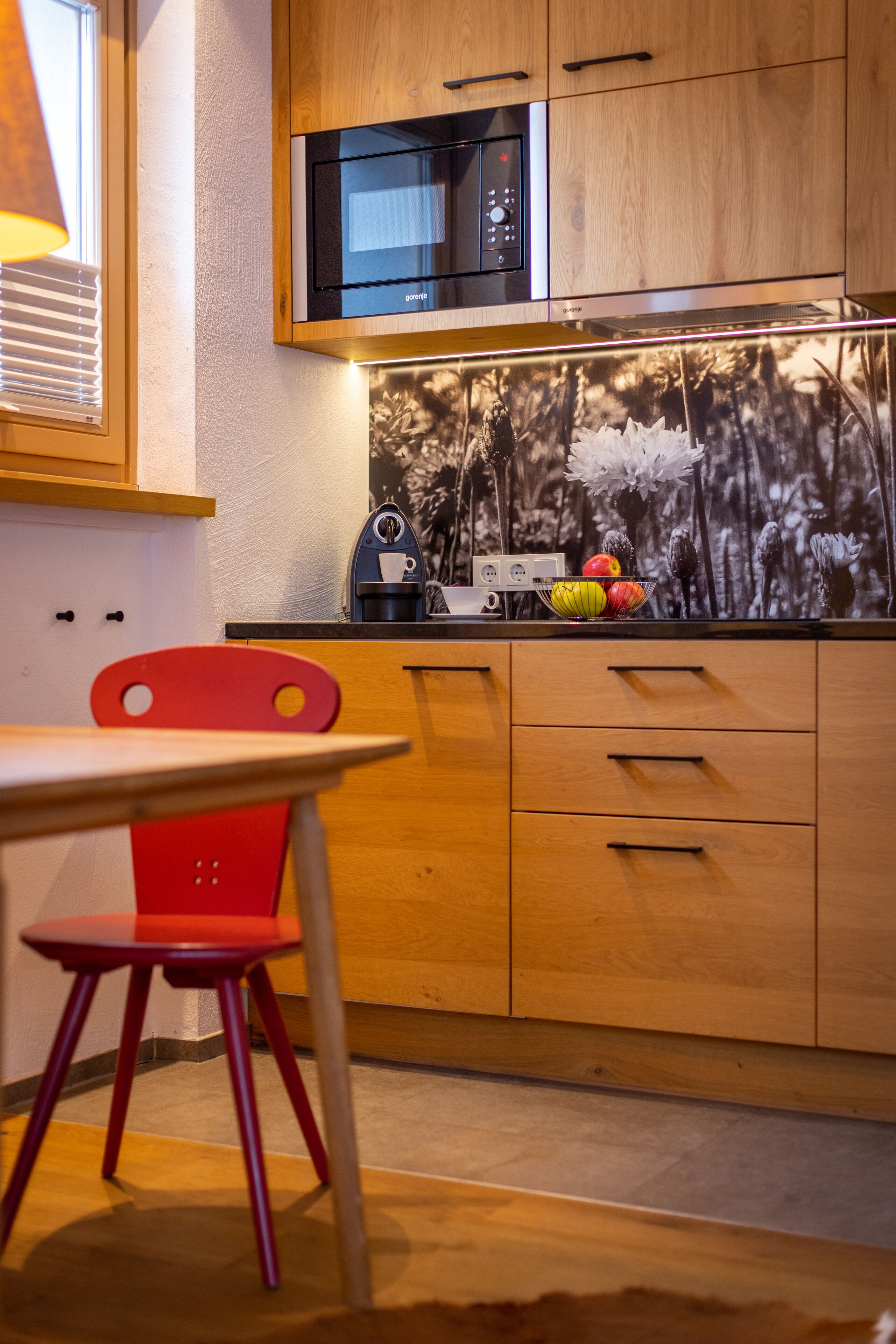 A kitchen with wooden cabinets, a microwave, and a fruit bowl on the counter.