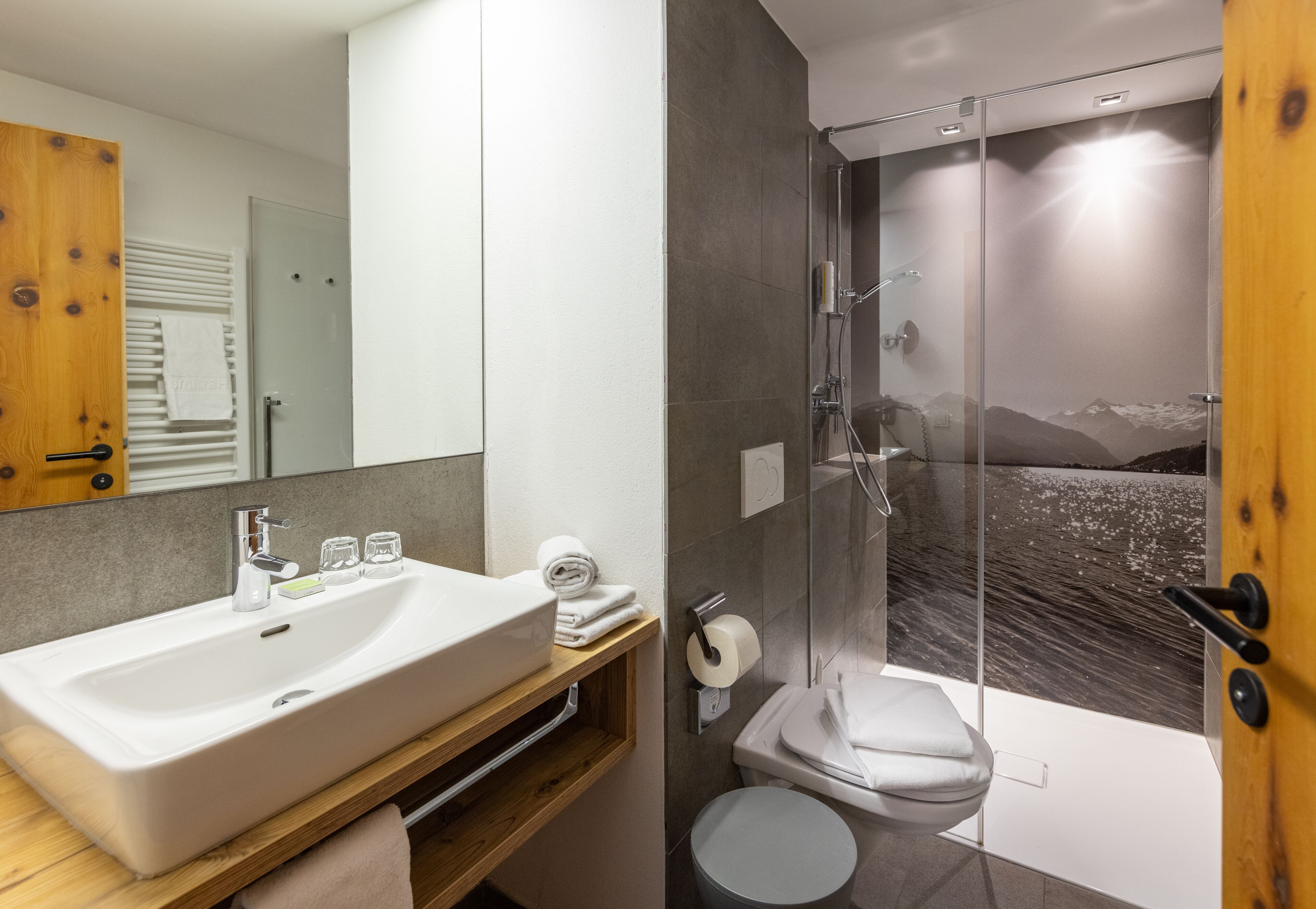 Un baño moderno con un lavamanos grande, espejo y ducha.
