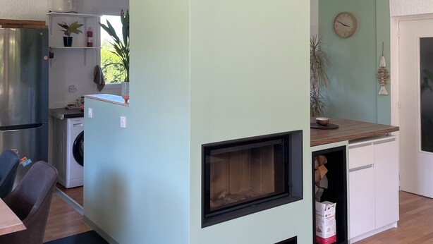Een moderne keuken met een ingebouwde kookplaat, een eethoek met tafel en stoelen, en een wasmachine.