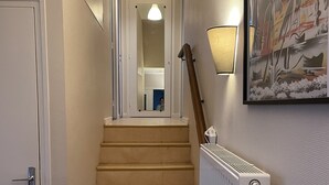 Een trap met een leuning, een radiator en een lijst met een kunstwerk aan de muur.