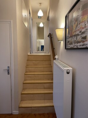 A staircase with a handrail, a radiator, and a framed artwork on the wall.