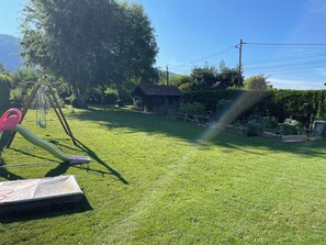 Une cour gazonnée avec une balançoire, un petit abri de jardin et une clôture.