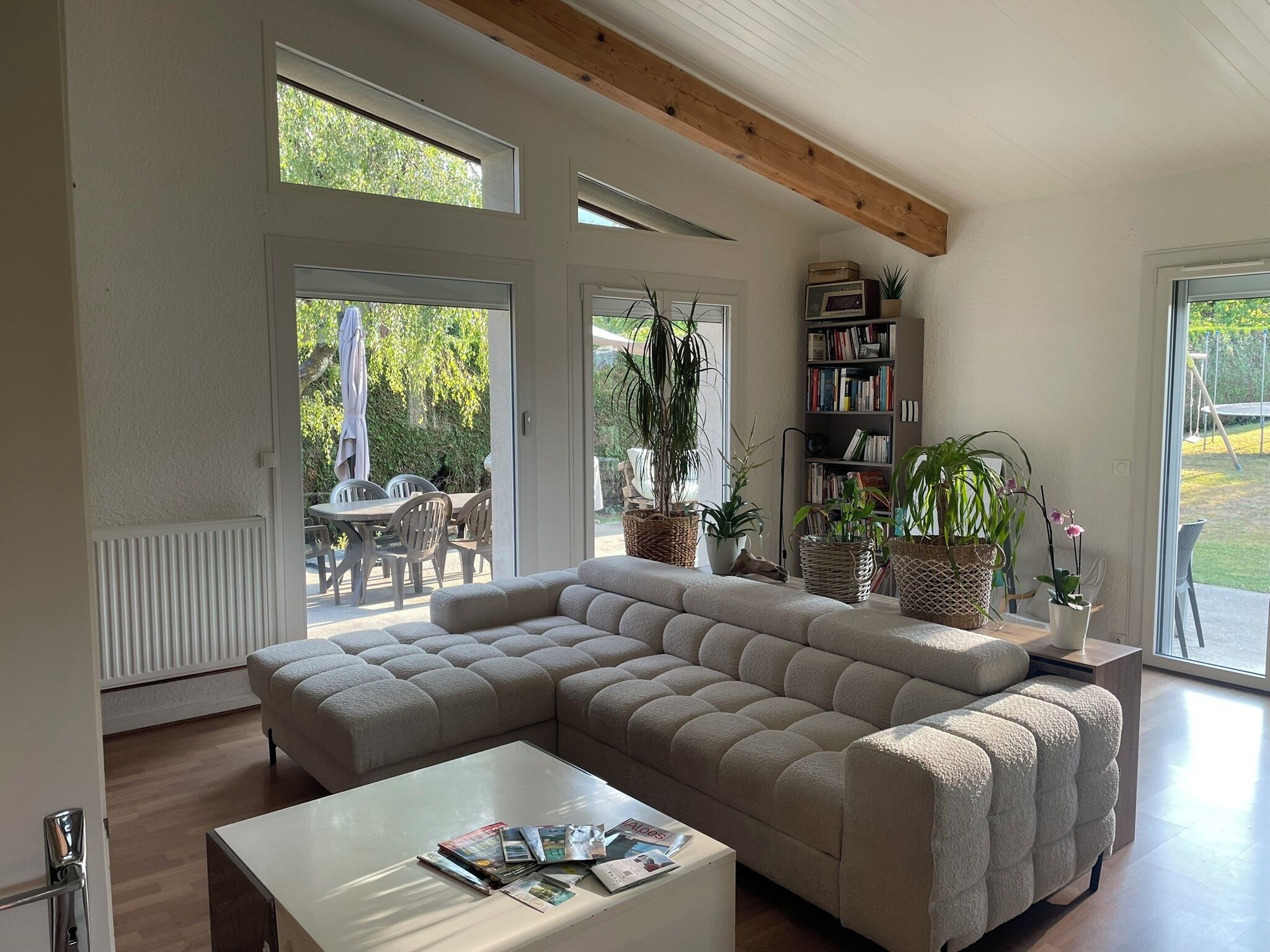 A modern living room with a sectional sofa, a coffee table, and a bookshelf.