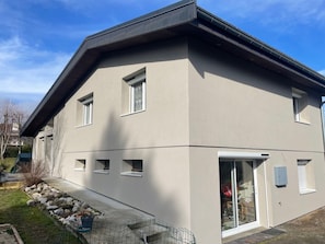 A modern two-story building with a flat roof, large windows, and a visible garage door.