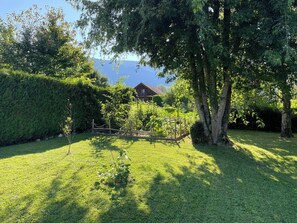 Un jardin bien entretenu, avec une clôture en bois, une variété d’arbres et une maison en arrière-plan.