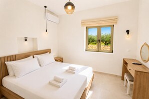 A bedroom with a bed, bedside tables, a desk, a mirror, and a window with a view of trees.
