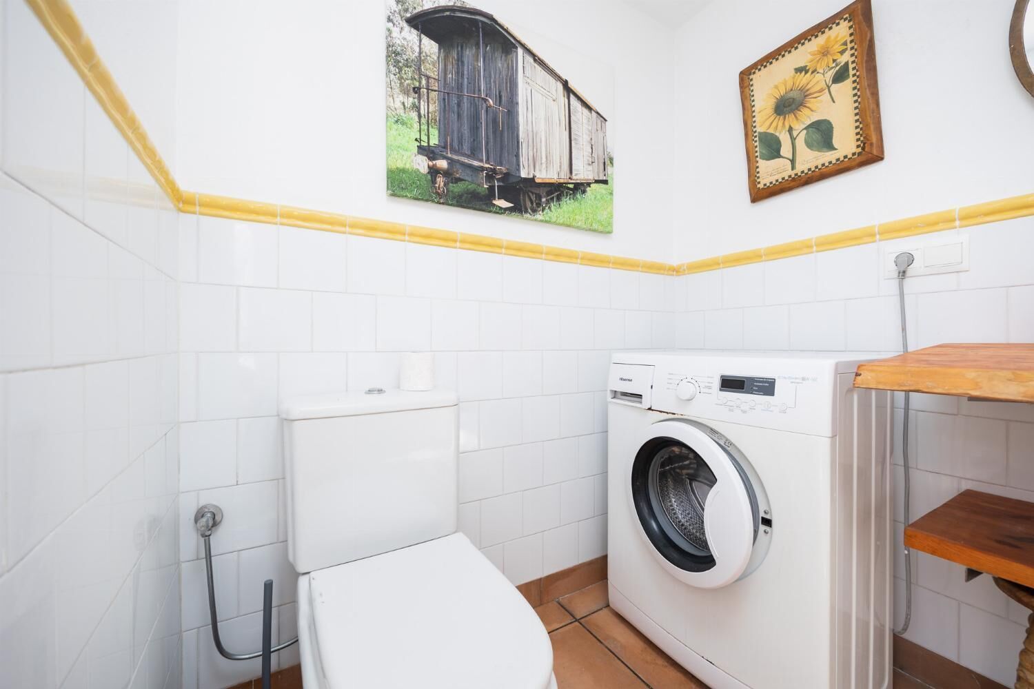 Ett litet, rent tvättrum med en tvättmaskin, en toalett och ett handfat.