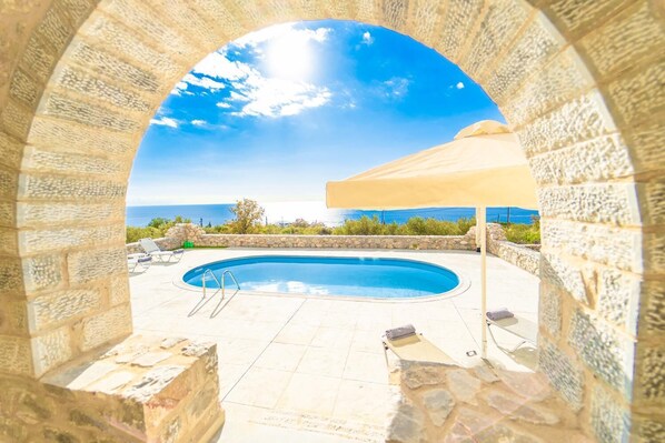 Ein Steinkorridor rahmt einen Pool mit Blick auf das Meer.