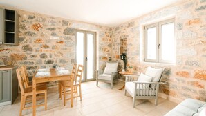 A cozy room with a stone wall, a dining table with chairs, a sofa, and a small table with a plant.