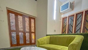 Une pièce avec un canapé vert, une table ronde blanche et une porte dont les panneaux sont en verre dépoli.