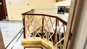 Un escalier au sol en marbre, avec une rampe en bois et une porte sur le côté droit.