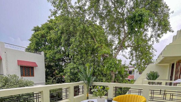 Une terrasse sur le toit, avec deux chaises jaunes et une petite table, entourée de gazon artificiel vert et d’un grand arbre.