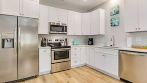 Una cocina moderna con armarios blancos, electrodomésticos de acero inoxidable y suelo de madera.