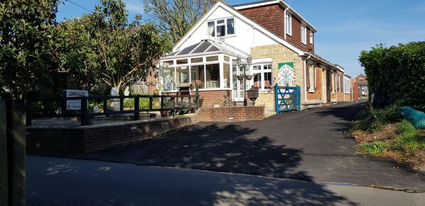 A two-story building with a conservatory, a brick facade, and a blue gate.