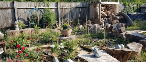 Un jardín con diversas plantas, una estructura de madera y un comedero para pájaros.