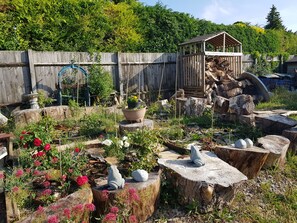 Un jardín con diversas plantas, una estructura de madera y un comedero para pájaros.