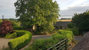A residential area with a large tree, a house with a sloped roof, and a well-maintained garden. - Shiralee Holiday Home (Salisbury)