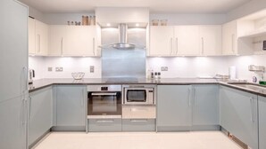Une cuisine moderne dotée d’appareils électroménagers en acier inoxydable, de meubles de couleur bleu clair et d’un îlot central.