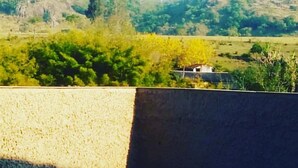 Una piscina con vistas a colinas verdes y una casa a lo lejos.
