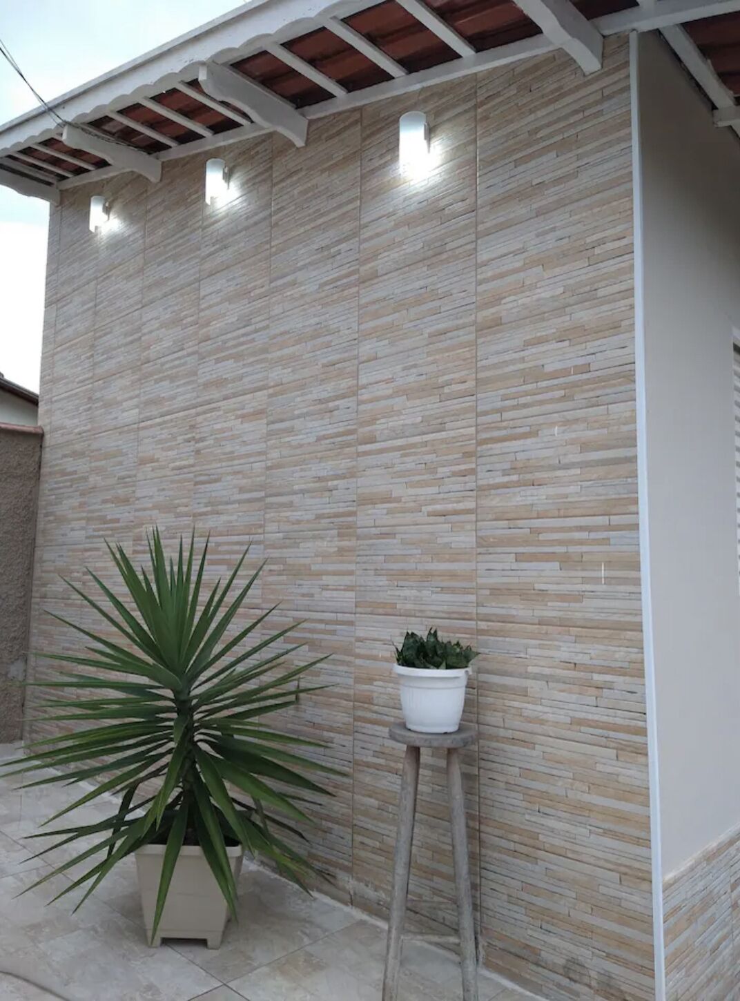 A building facade with a stone-textured exterior, a potted plant, and a small white planter.