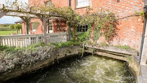 A brick building with a small stream running through it. - The Happy Hut (Christchurch)