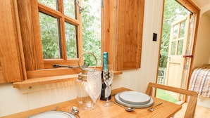 A wooden dining table set with plates, cutlery, and a glass. - The Happy Hut (Christchurch)