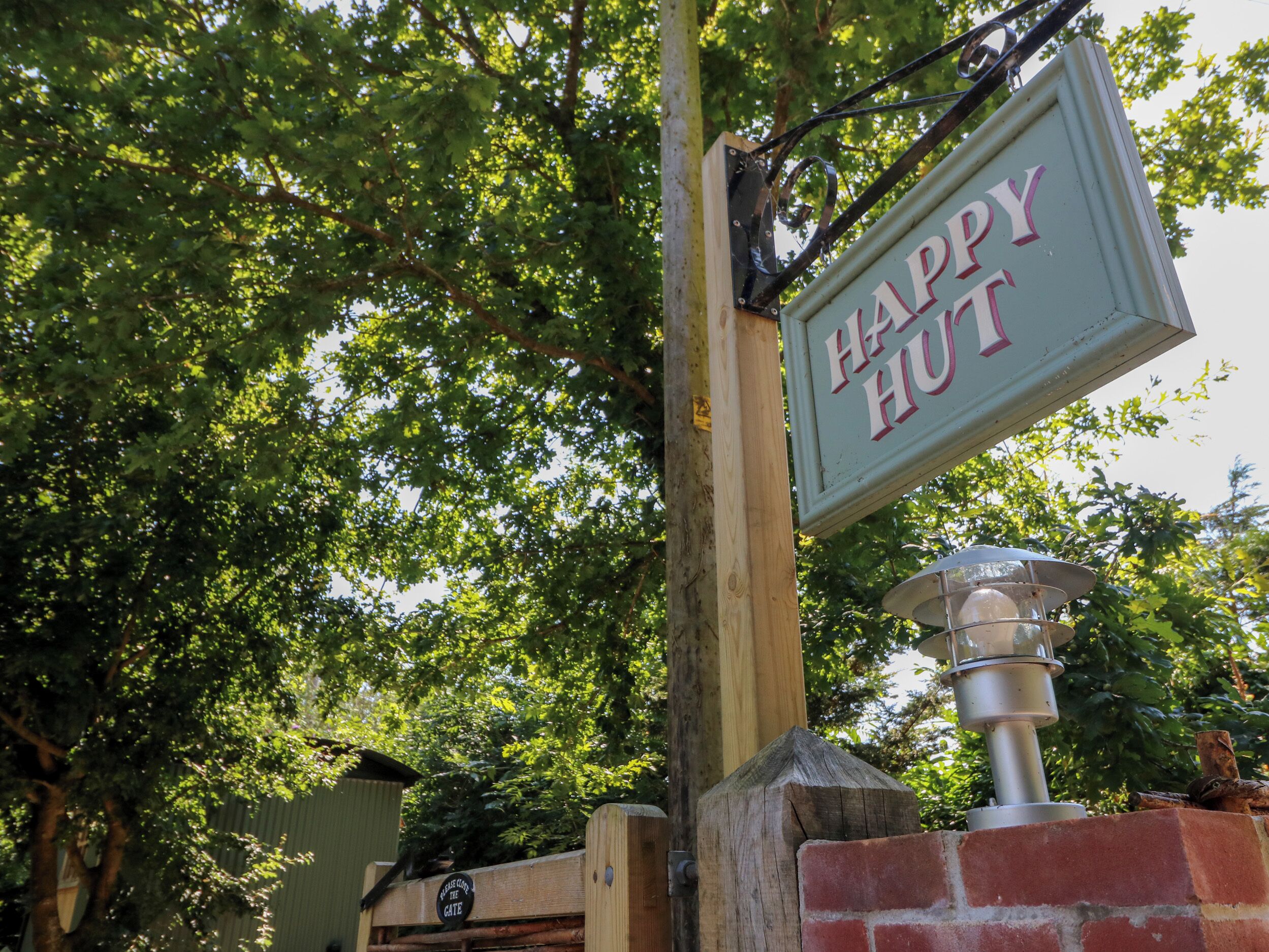 Un poteau en bois sur lequel est fixée une plaque métallique portant l’inscription « HAPPY HUT ».