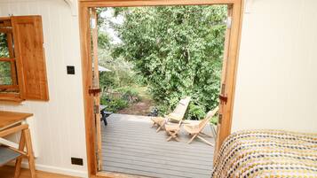 Una habitación con puerta de madera que da a un patio exterior con dos sillas y una mesa de madera.