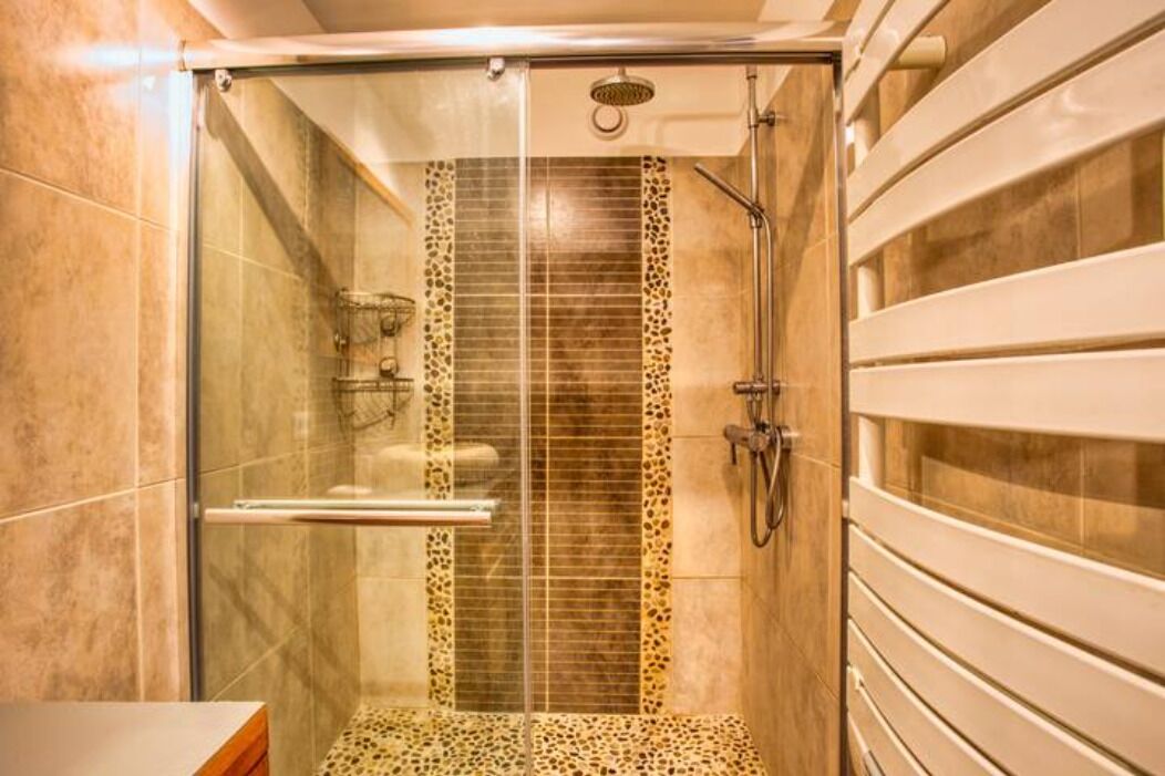Un baño moderno con ducha envuelta en vidrio, un muro decorado con estampado de leopardo y un mueble de tocador elegante.