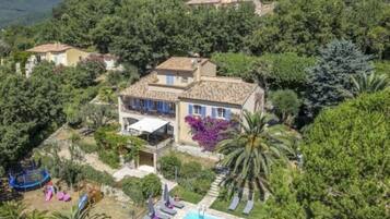 Una villa con piscina rodeada de exuberante vegetación y vistas a la colina.