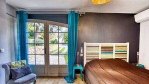 Un dormitorio con una cama grande, una silla, una ventana con cortinas y un radiador.