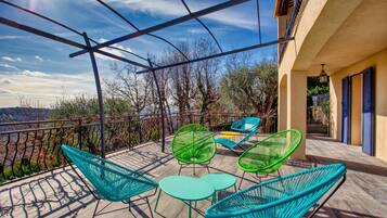 Una terraza con sillones y mesas de mimbre, con vistas a un paisaje pintoresco.