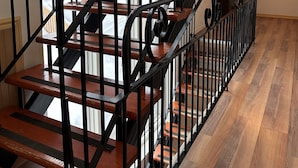 Un escalier en bois avec des rampes noires et une vue sur l’extérieur.