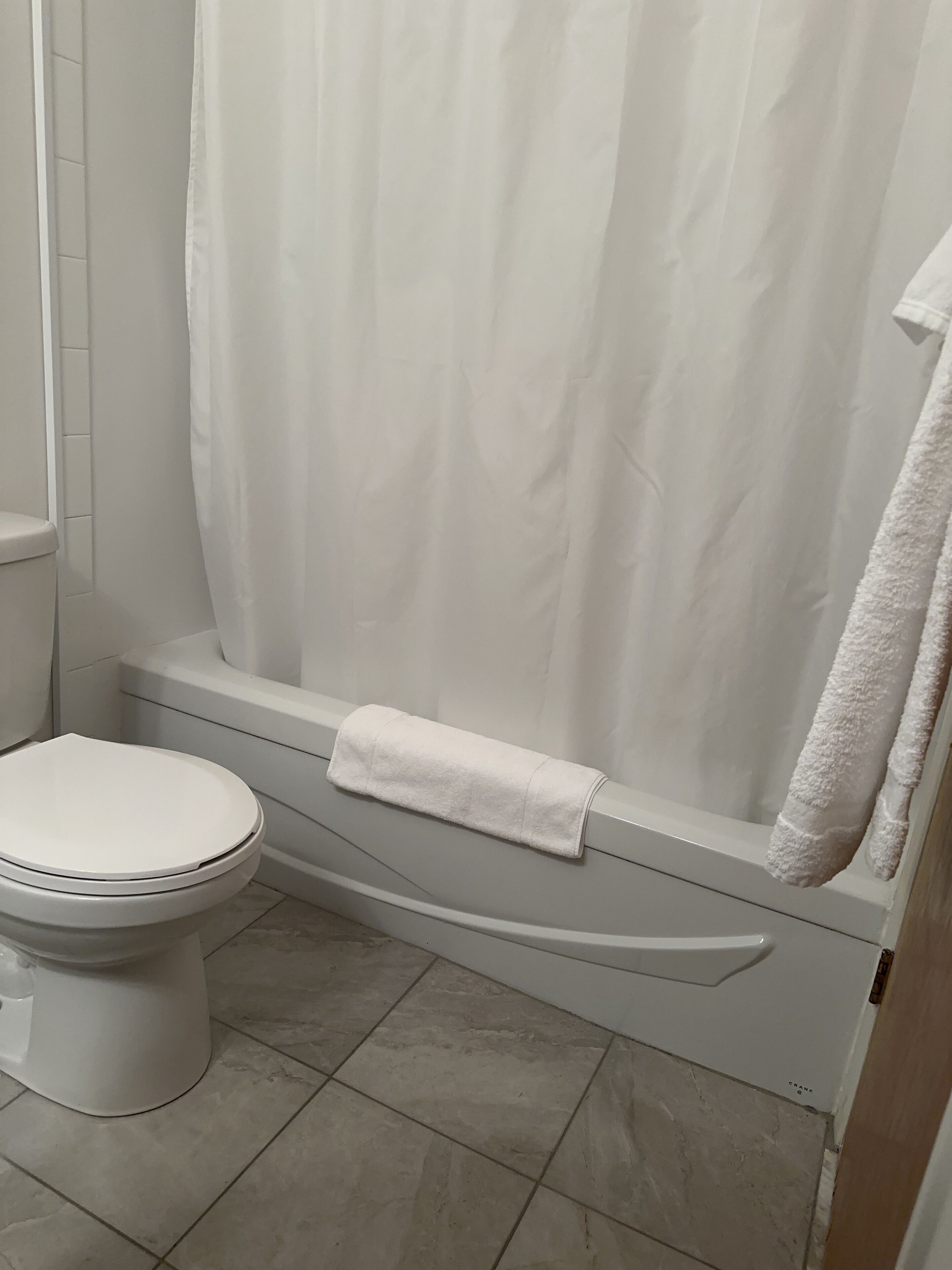 Une salle de bain avec des toilettes, une baignoire avec une serviette blanche et un rideau de douche.