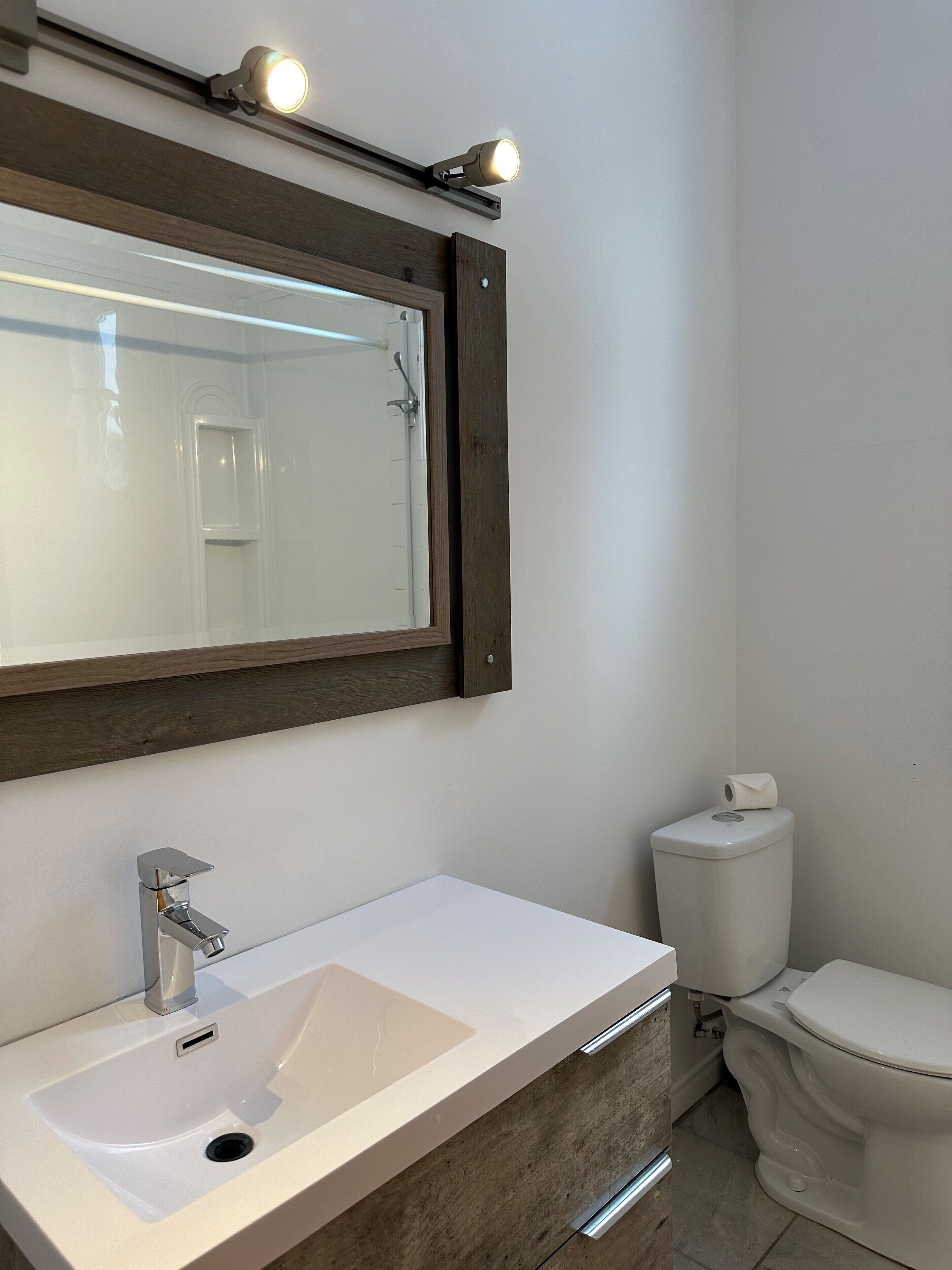 A bathroom with a white sink, a mirror, and a toilet.