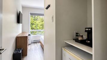 Cocina compacta con refrigerador, cafetera y ventana con vista a follaje.