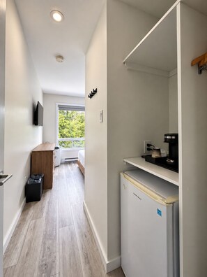 Cocina compacta con refrigerador, cafetera y ventana con vista a follaje.