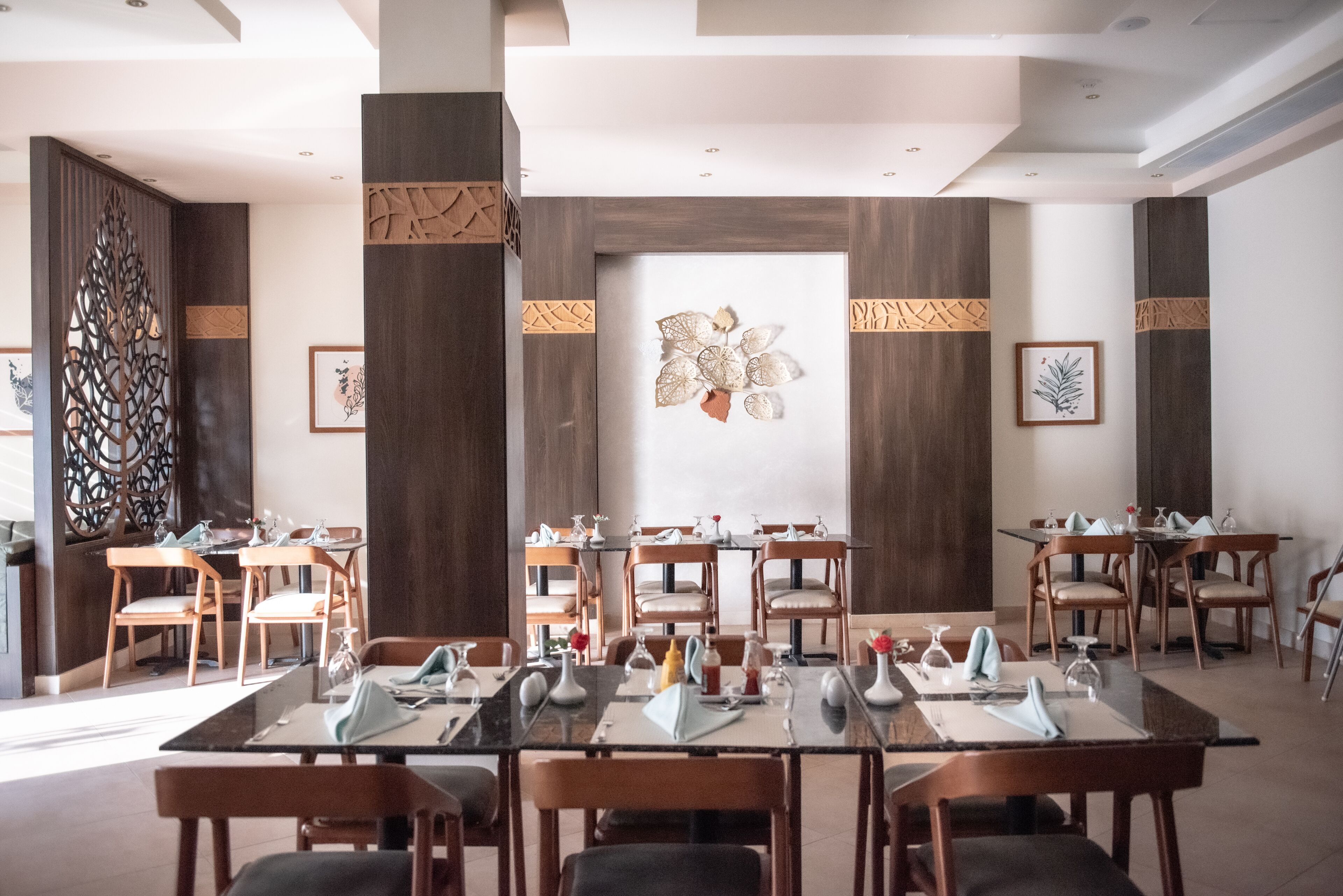 Un salón de conferencias con varias mesas y sillas, paneles de madera y obras de arte enmarcadas en las paredes.