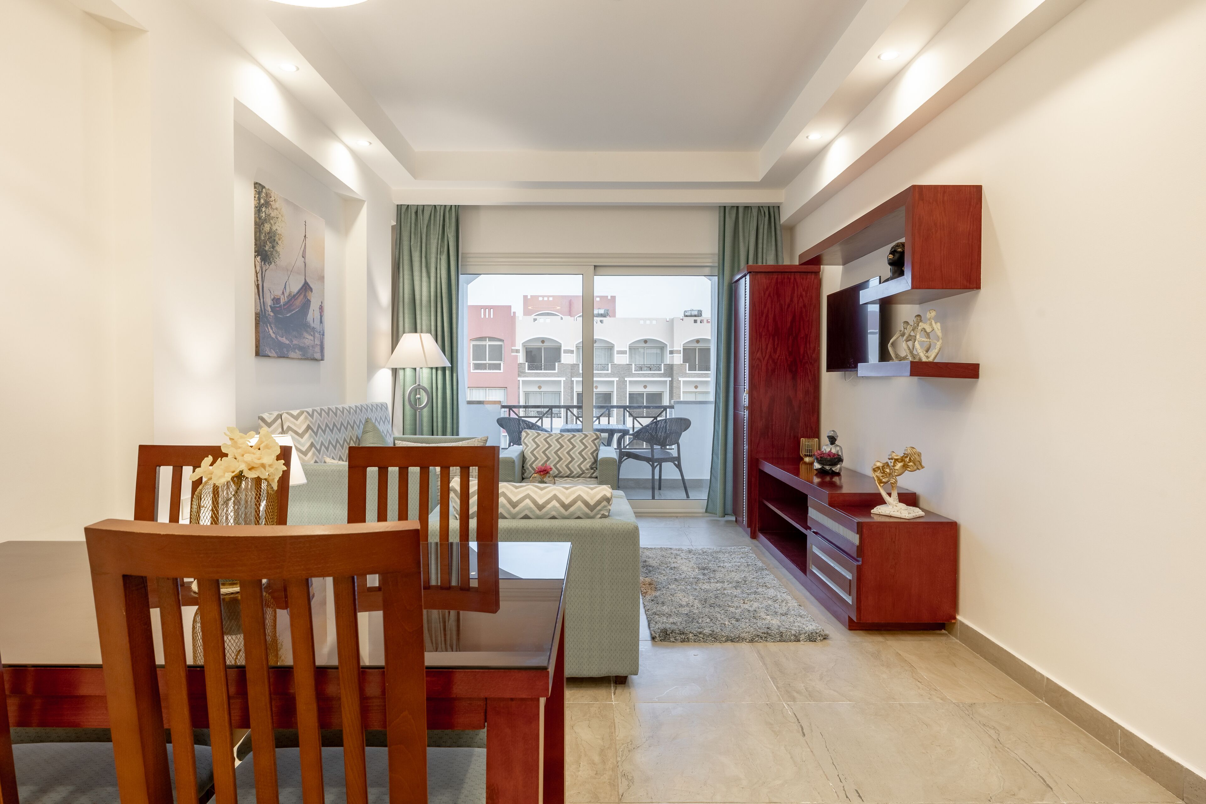 A modern living room with a dining area, a sofa, a TV stand, and a balcony with a view of buildings.